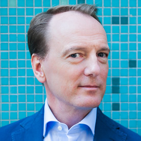 Marc Elsberg steht vor einem Mosaik.